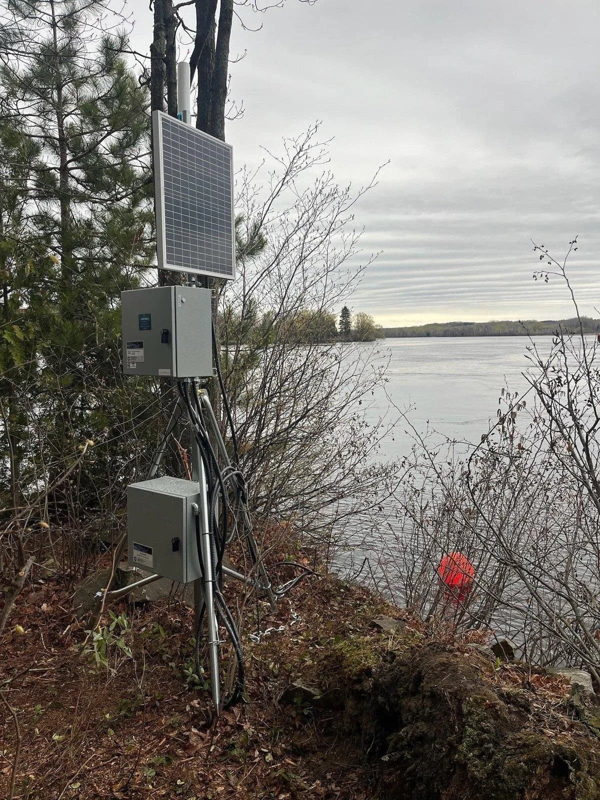 Solar-powered water monitoring station on a riverbank